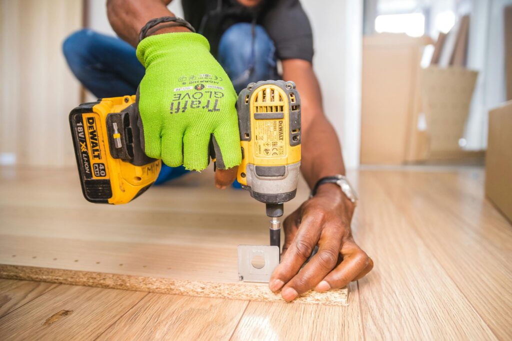 Inicio Man using a power drill for home improvement on a wooden floor with precision.
